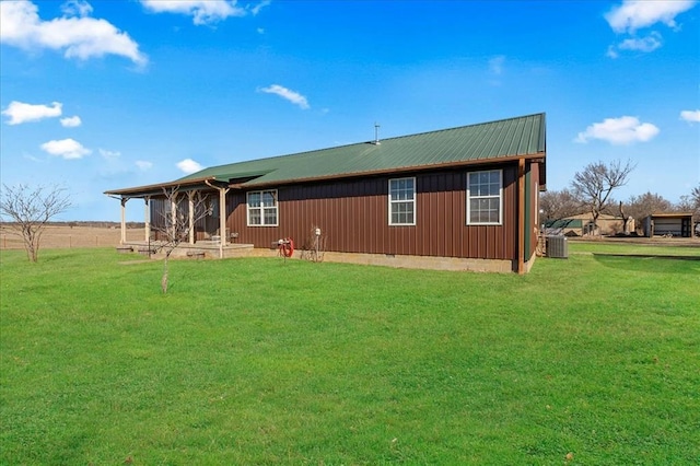 rear view of house with cooling unit, metal roof, and a lawn