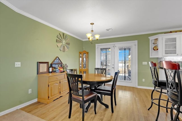 dining room featuring baseboards, light wood-style flooring, visible vents, and crown molding