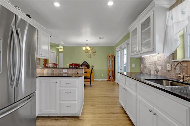 kitchen featuring freestanding refrigerator, white cabinetry, a sink, and dark countertops