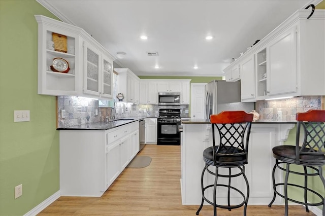 kitchen with dark countertops, stainless steel appliances, a peninsula, and visible vents