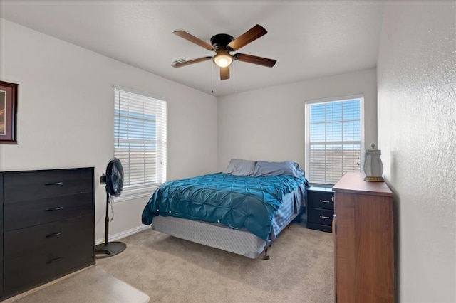 bedroom with light carpet, baseboards, a ceiling fan, and a textured wall