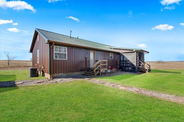 back of house with board and batten siding, crawl space, a yard, and metal roof