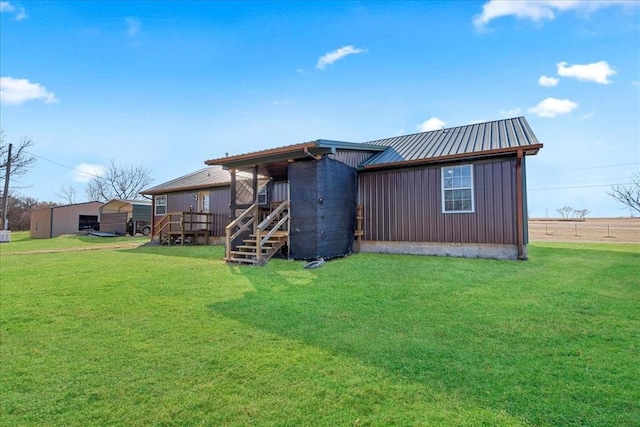 back of property with metal roof, a yard, and board and batten siding