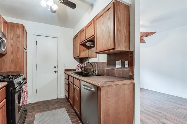 kitchen featuring sink, ceiling fan, appliances with stainless steel finishes, backsplash, and dark hardwood / wood-style flooring