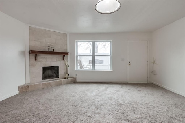 unfurnished living room with a tiled fireplace and carpet flooring