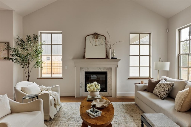 living room with lofted ceiling, a high end fireplace, and light hardwood / wood-style floors