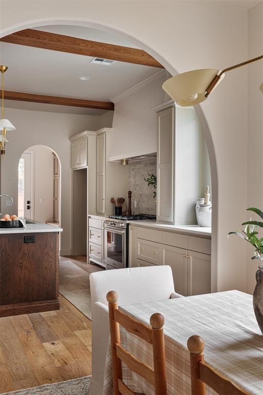 kitchen with light wood-type flooring, sink, stainless steel stove, and white cabinets