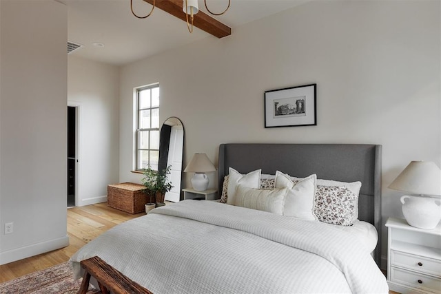 bedroom with beamed ceiling and light hardwood / wood-style flooring