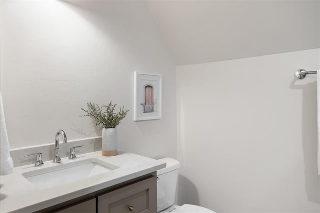 bathroom featuring vanity, vaulted ceiling, and toilet