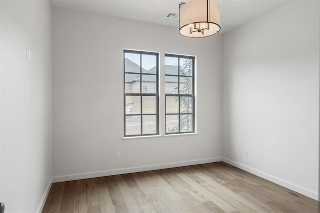 spare room featuring an inviting chandelier and light hardwood / wood-style floors