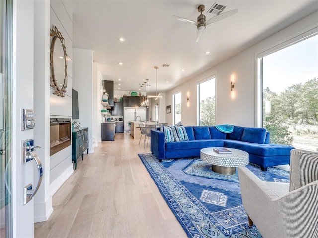 living area featuring light wood-style floors, ceiling fan, visible vents, and recessed lighting