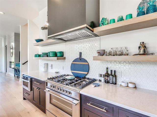 kitchen with premium range hood, dark brown cabinets, high end range, open shelves, and tasteful backsplash