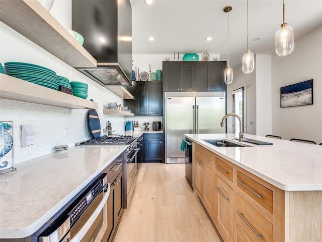 kitchen featuring a kitchen island with sink, island range hood, a sink, open shelves, and high end appliances