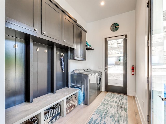 laundry room featuring baseboards, light wood finished floors, cabinet space, and washer and dryer