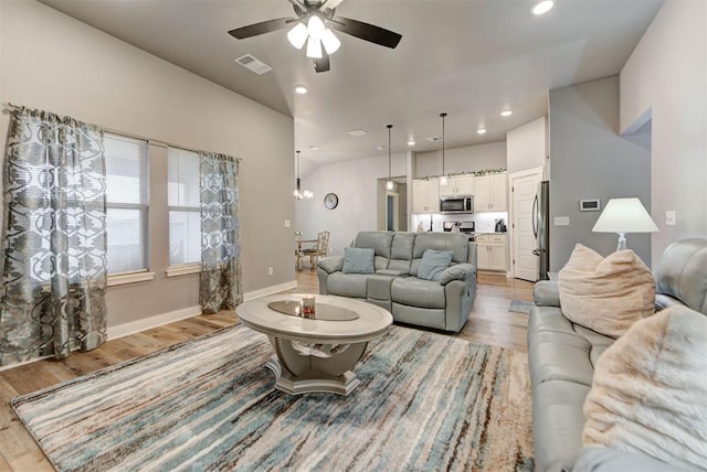 living room with ceiling fan and light hardwood / wood-style flooring