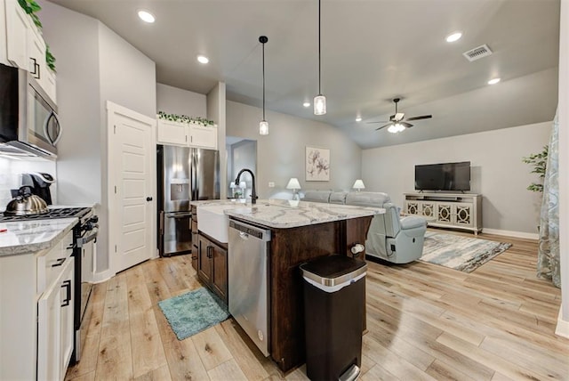 kitchen featuring pendant lighting, white cabinets, stainless steel appliances, dark brown cabinets, and a center island with sink