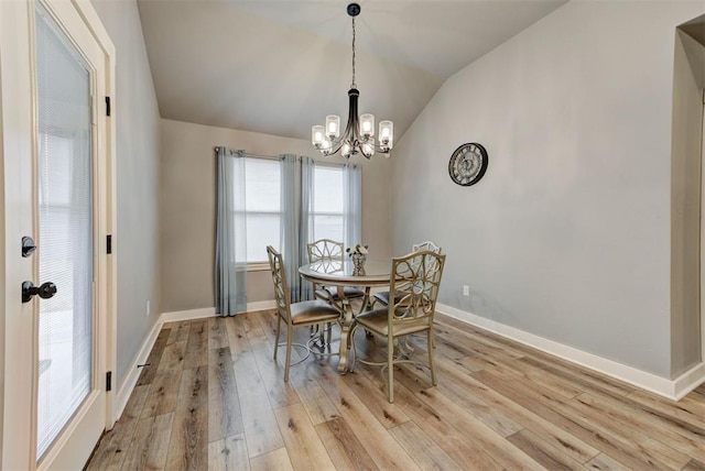 dining area featuring an inviting chandelier, lofted ceiling, and light hardwood / wood-style floors