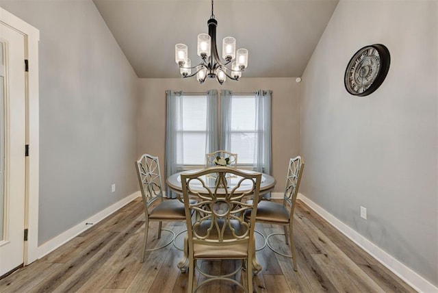 dining room featuring hardwood / wood-style flooring, lofted ceiling, and an inviting chandelier