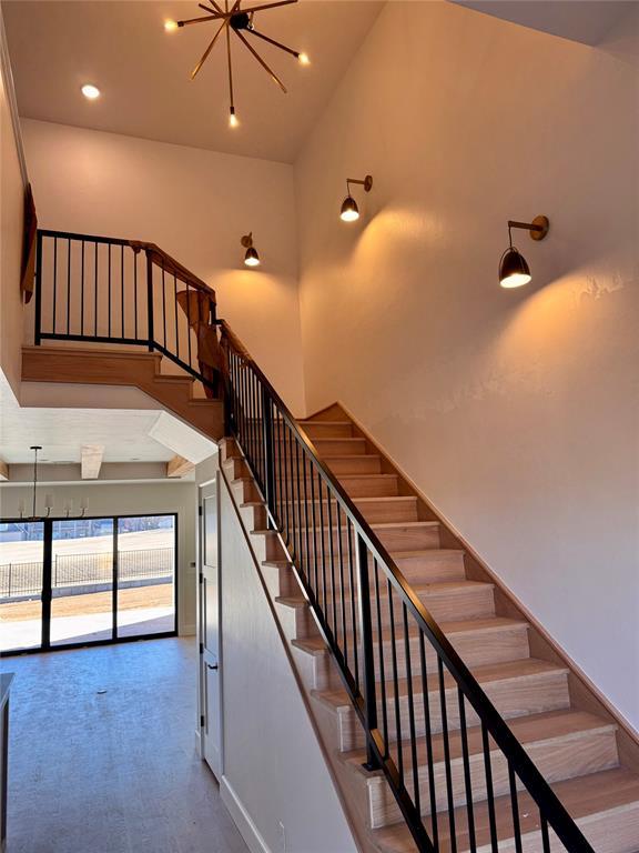 staircase with an inviting chandelier and a towering ceiling