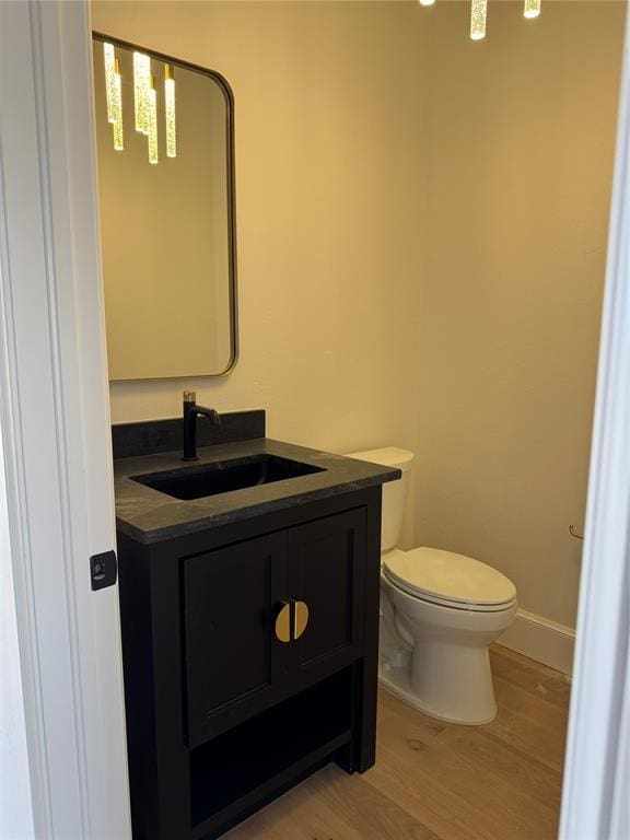 bathroom featuring baseboards, vanity, toilet, and wood finished floors