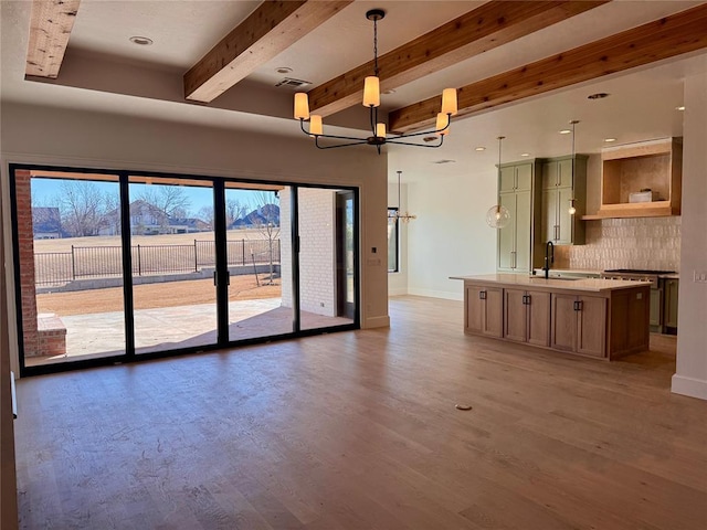 unfurnished living room with visible vents, baseboards, dark wood-style flooring, beamed ceiling, and a sink