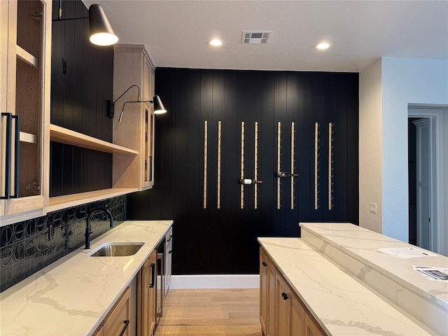 kitchen with light stone counters, a sink, visible vents, light wood-type flooring, and open shelves