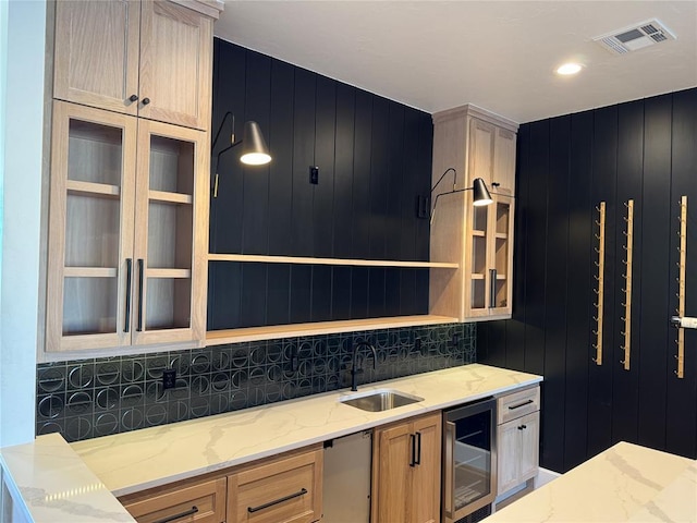 kitchen with wine cooler, visible vents, light brown cabinets, a sink, and light stone countertops