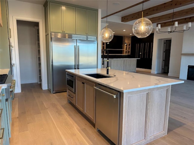 kitchen with open floor plan, light stone counters, an island with sink, and a sink