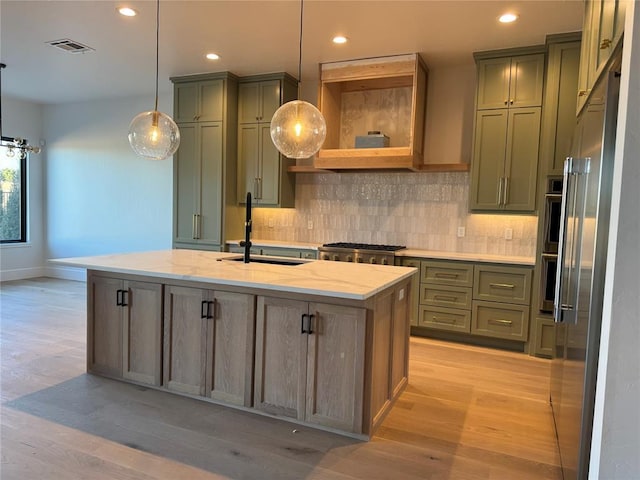 kitchen with visible vents, appliances with stainless steel finishes, light stone countertops, an island with sink, and decorative light fixtures