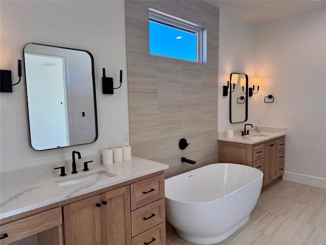 bathroom featuring a freestanding tub, two vanities, a sink, and baseboards