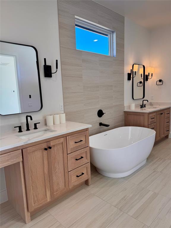 bathroom featuring a freestanding bath, two vanities, and a sink