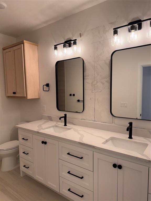 bathroom featuring a sink, toilet, and double vanity