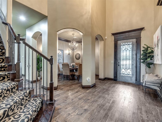 entryway with a towering ceiling, wood-type flooring, and a notable chandelier