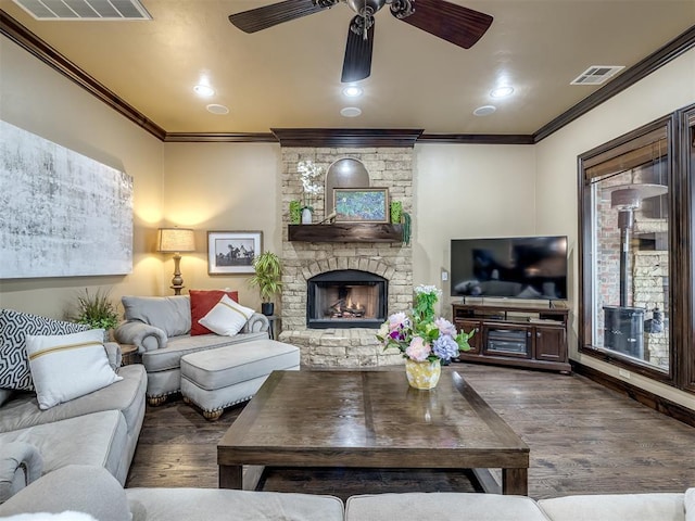 living room featuring crown molding, a stone fireplace, dark hardwood / wood-style floors, and ceiling fan