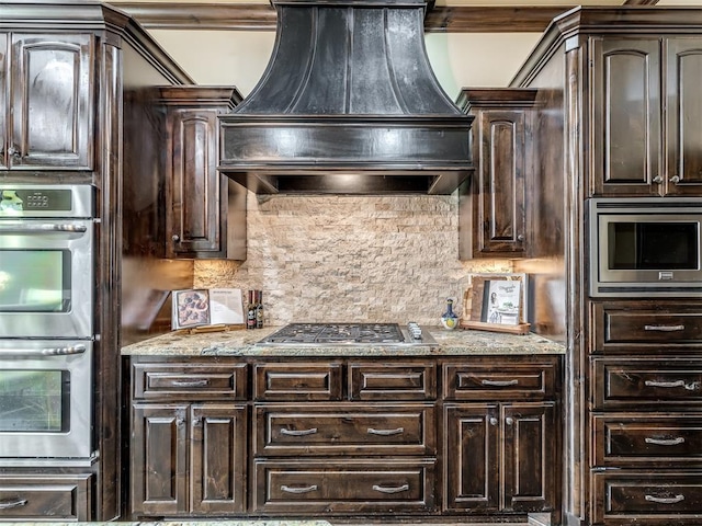 kitchen featuring premium range hood, decorative backsplash, appliances with stainless steel finishes, and dark brown cabinets