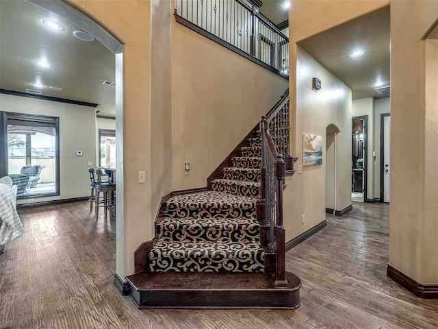 staircase with wood-type flooring and ornamental molding