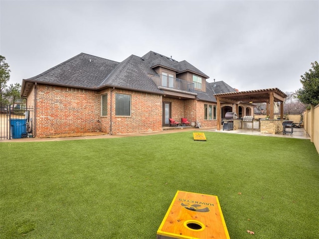 back of house featuring a patio, a pergola, exterior kitchen, and a lawn