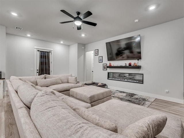 cinema room with hardwood / wood-style floors and ceiling fan