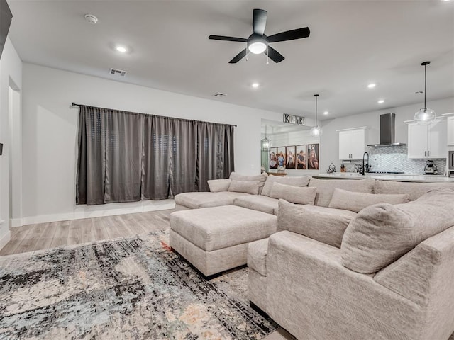 living room with ceiling fan, sink, and light hardwood / wood-style floors