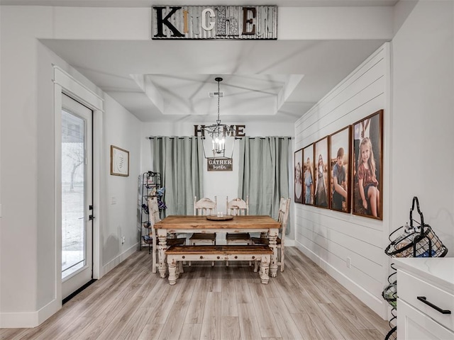 dining area with a raised ceiling, a healthy amount of sunlight, and light wood-type flooring