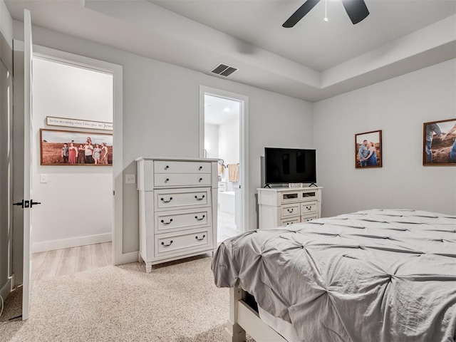 bedroom featuring connected bathroom, a raised ceiling, and ceiling fan