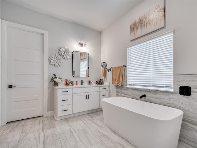 bathroom with vanity, a washtub, and tile walls