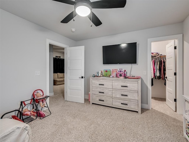 carpeted bedroom with a walk in closet, a closet, and ceiling fan