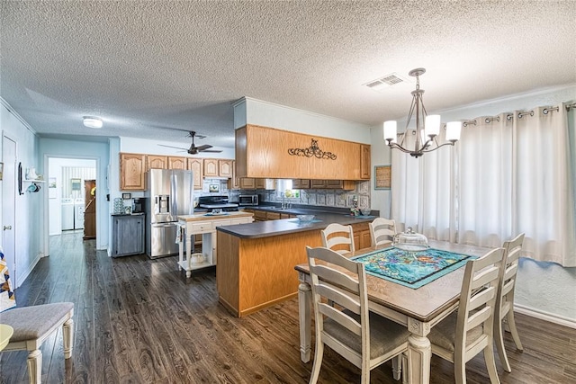 kitchen with dark wood-type flooring, tasteful backsplash, appliances with stainless steel finishes, kitchen peninsula, and pendant lighting