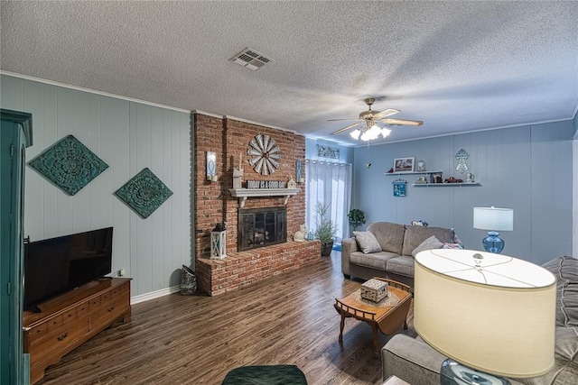 living room featuring ceiling fan, hardwood / wood-style floors, a textured ceiling, and a fireplace