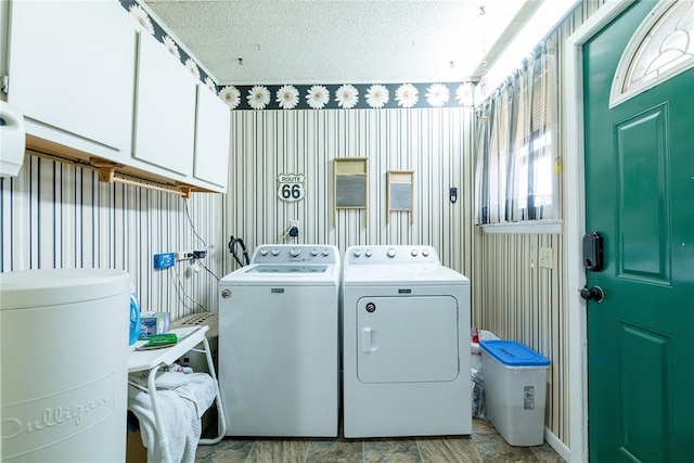 clothes washing area with independent washer and dryer, cabinets, and a textured ceiling