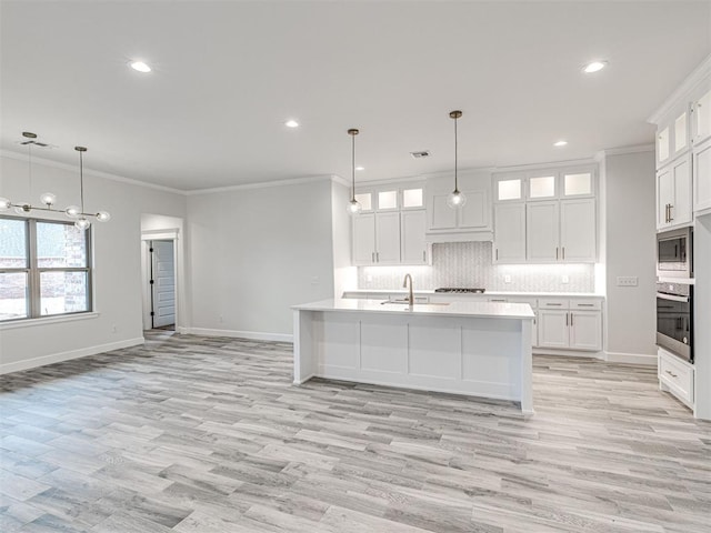 kitchen featuring white cabinetry, stainless steel appliances, and an island with sink