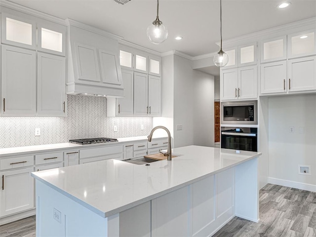 kitchen with pendant lighting, stainless steel gas stovetop, white cabinetry, sink, and oven