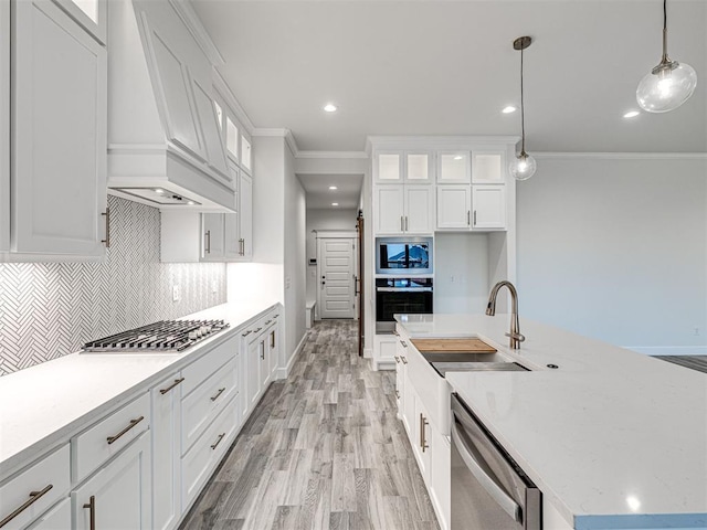 kitchen with stainless steel appliances, custom exhaust hood, hanging light fixtures, and white cabinets