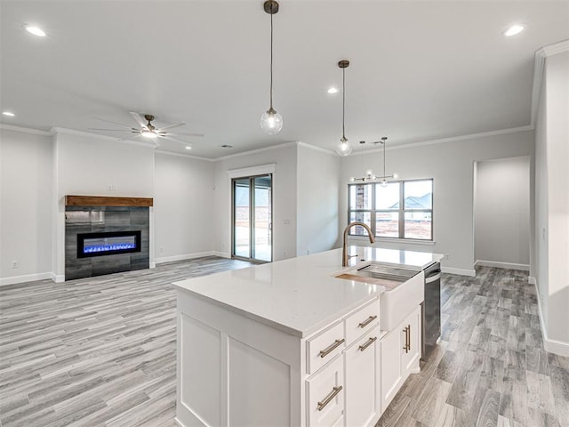 kitchen with sink, decorative light fixtures, a kitchen island with sink, and white cabinets